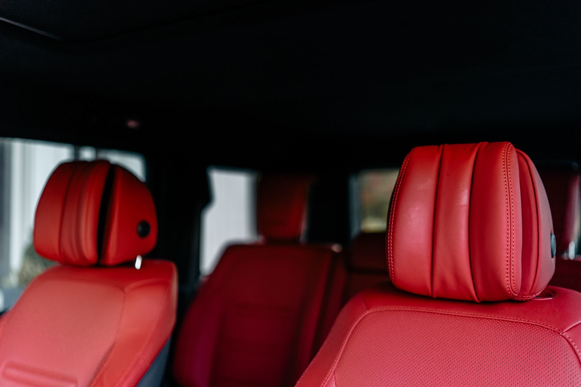 Close-up view of a luxury car interior with red leather seats and headrests.